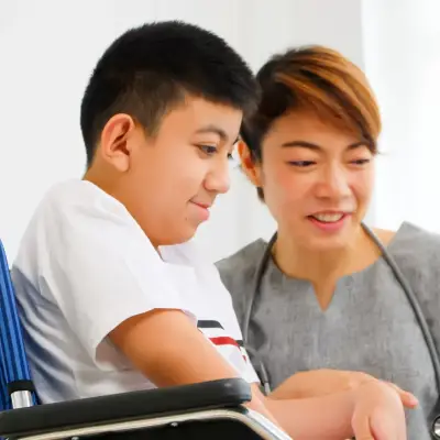 A therapist is talking to a disabled boy in a wheelchair